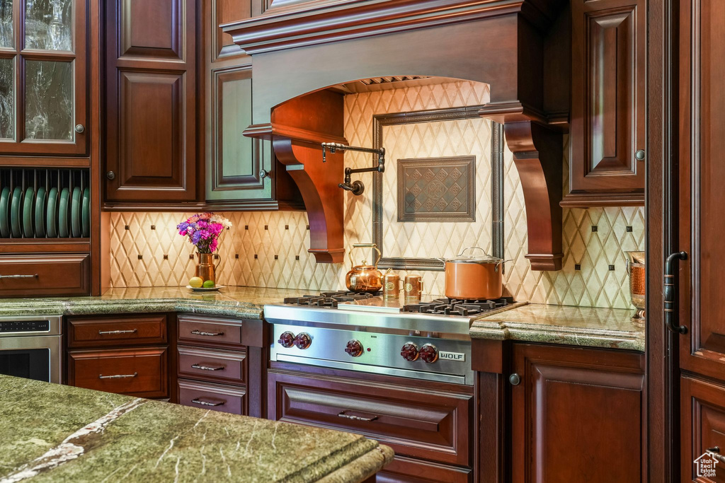 Kitchen featuring stainless steel appliances, decorative backsplash, and glass insert cabinets
