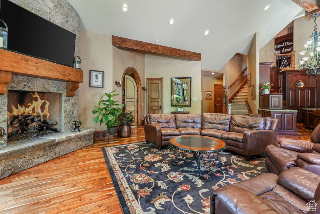Living area featuring hardwood / wood-style flooring, high vaulted ceiling, stairway, a fireplace, and recessed lighting