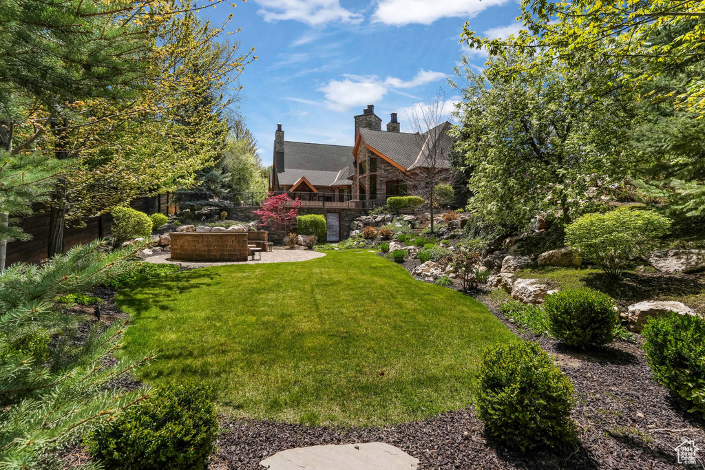 View of green lawn featuring a patio area and an outdoor fire pit