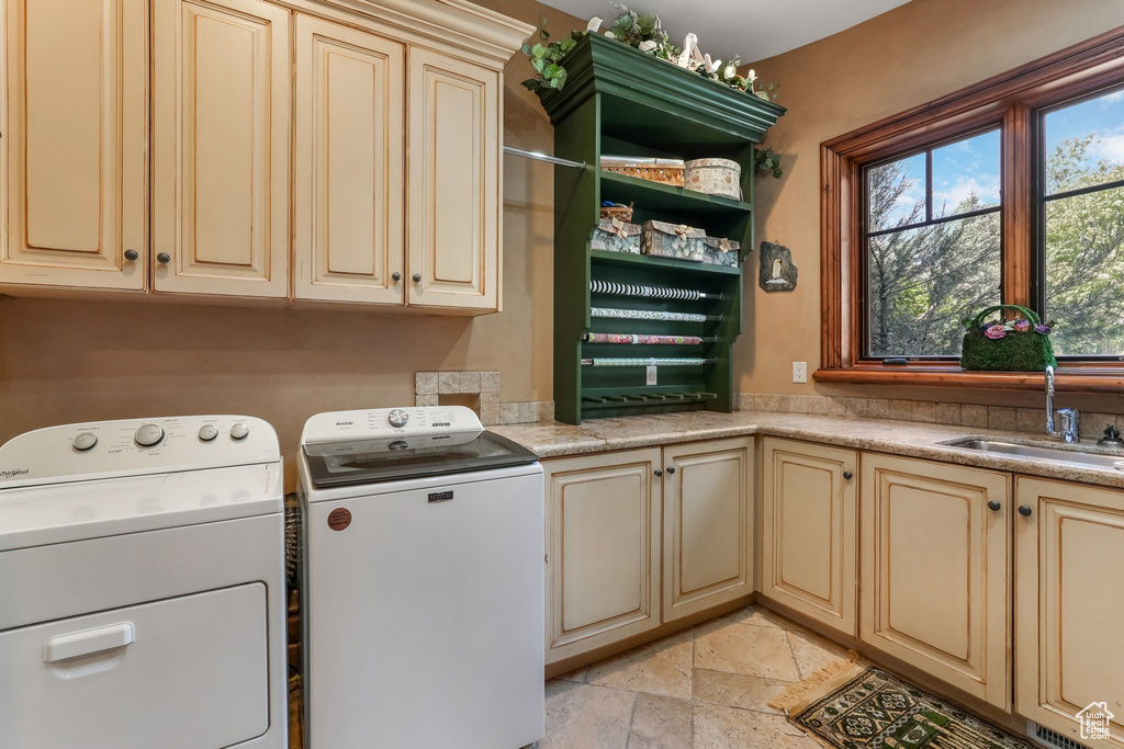 Laundry room featuring cabinet space, separate washer and dryer, and stone tile floors