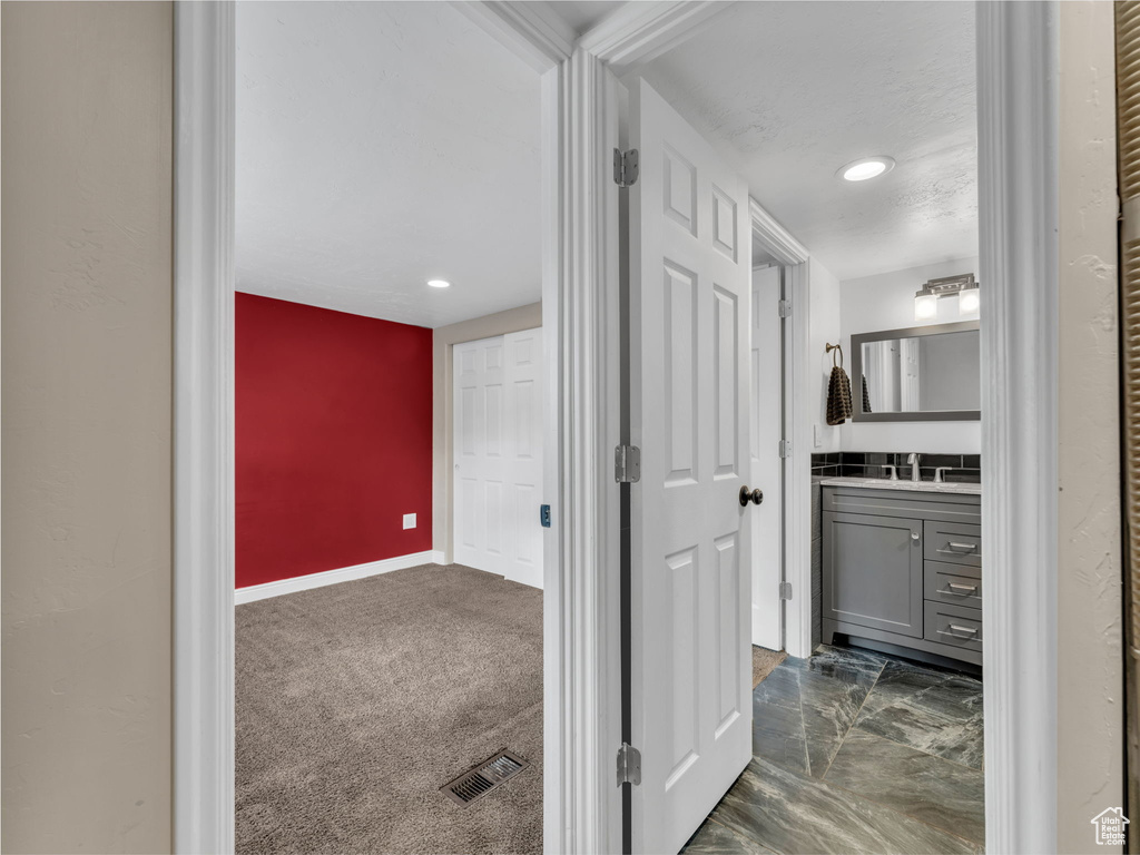 Corridor with a sink, baseboards, and recessed lighting