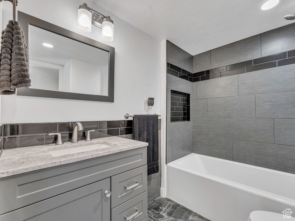 Full bathroom with vanity, marble look tile flooring, recessed lighting, shower / tub combination, and toilet
