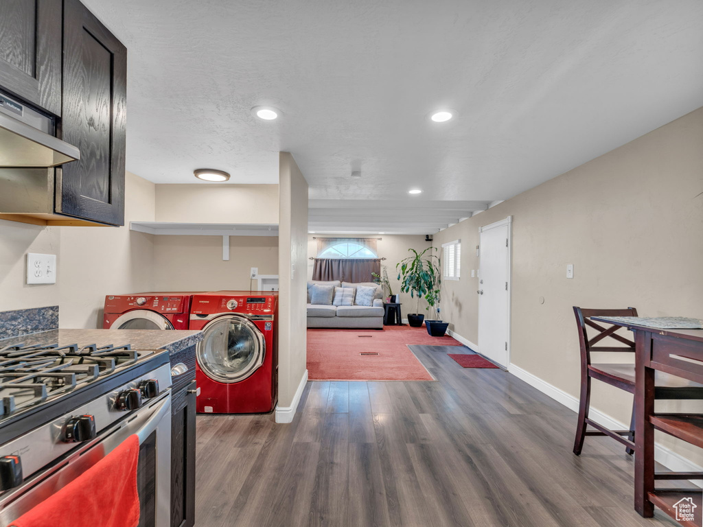 Kitchen featuring stainless steel gas range oven, washer and dryer, baseboards, recessed lighting, and dark wood-type flooring