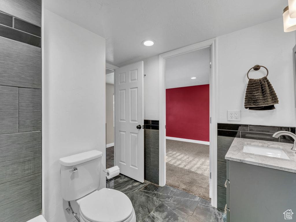 Bathroom with toilet, vanity, baseboards, and recessed lighting