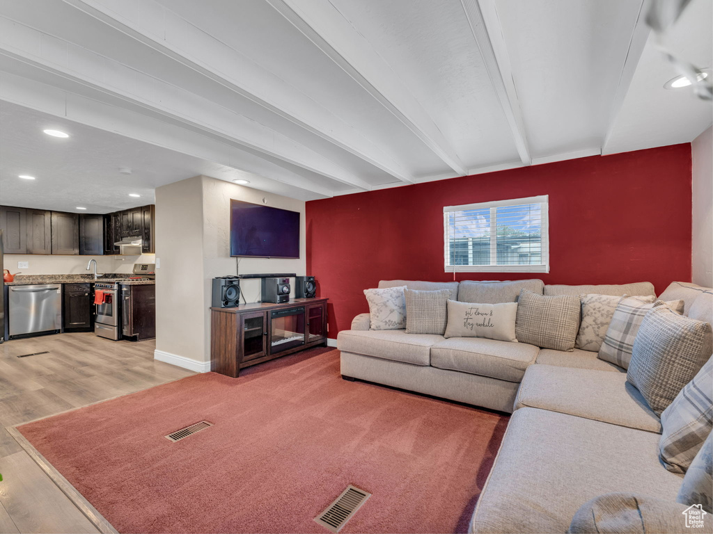 Living area featuring light wood-type flooring, beam ceiling, recessed lighting, and baseboards