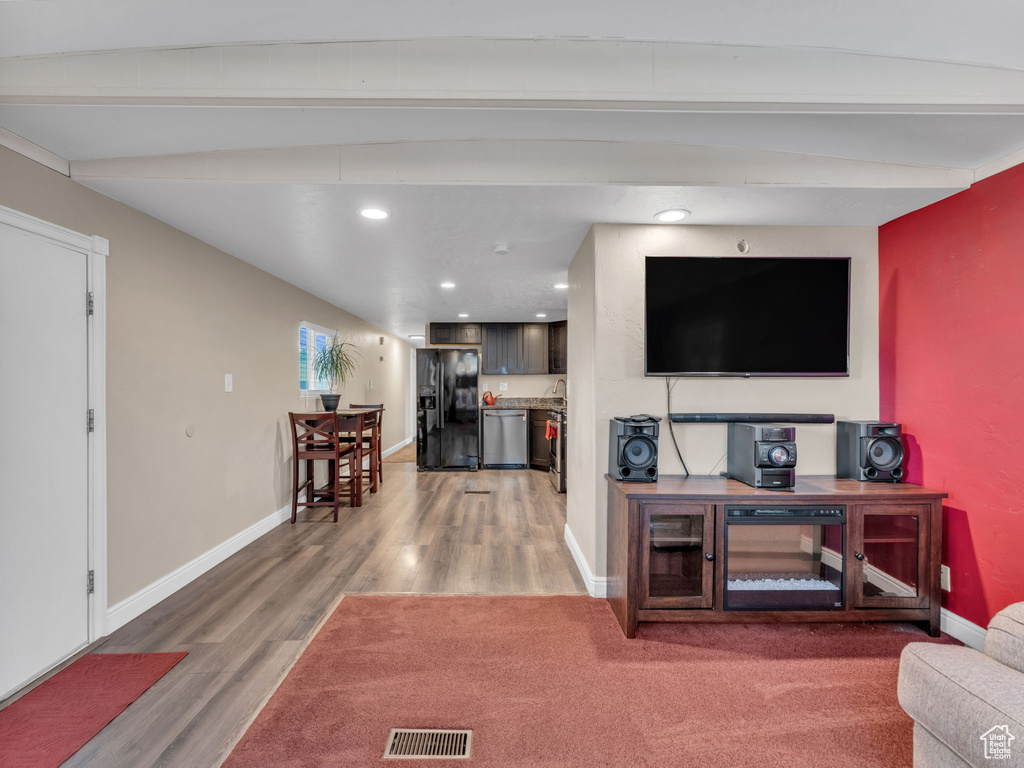 Living area with light wood-style floors, baseboards, recessed lighting, and beam ceiling