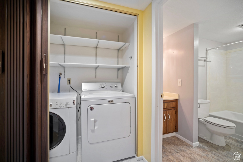 Laundry room with washer and dryer, light wood-type flooring, and baseboards