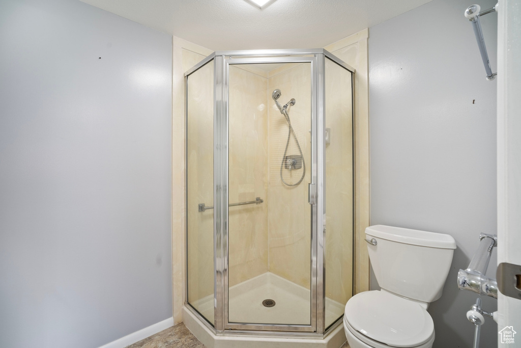 Full bathroom with toilet, a stall shower, and baseboards