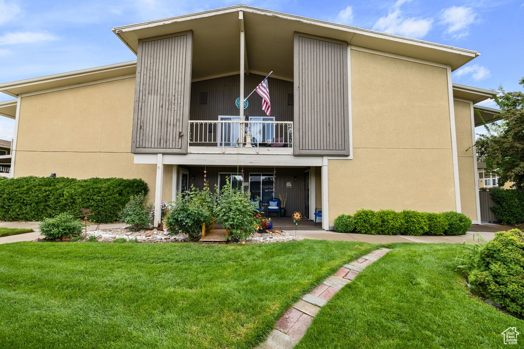 Rear view of property with a balcony and a lawn