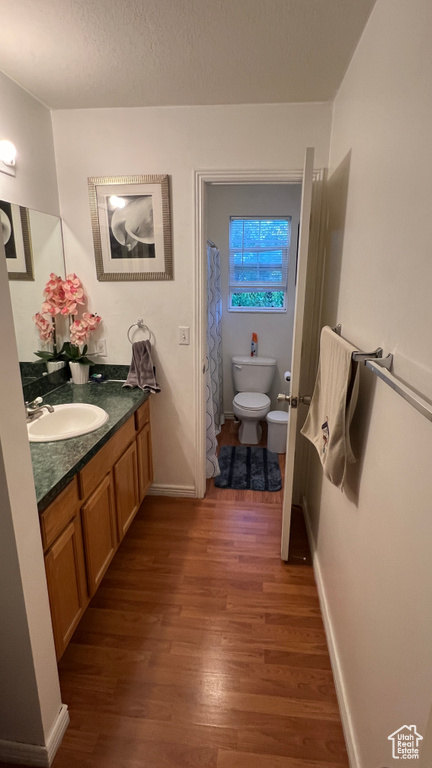 Bathroom with toilet, wood finished floors, vanity, and baseboards