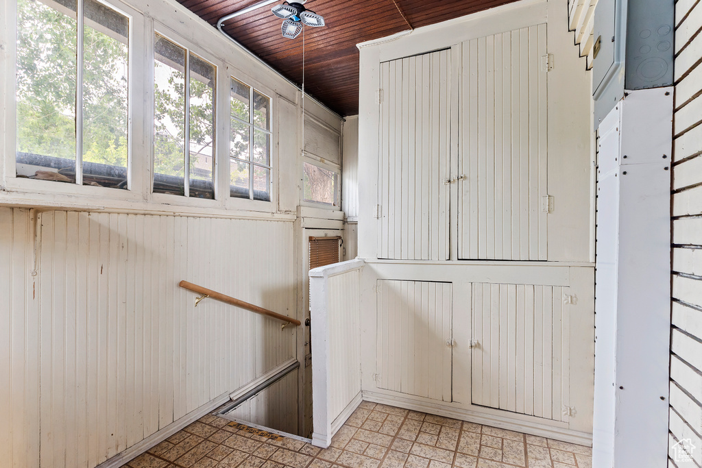 Staircase featuring wood ceiling, a ceiling fan, and wood walls