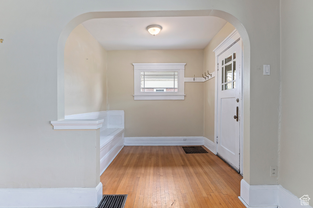 Foyer entrance with arched walkways, light wood-style floors, and baseboards