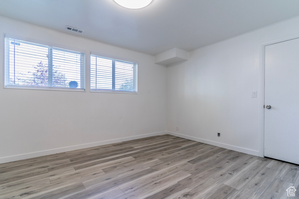 Spare room featuring healthy amount of natural light, light wood-style floors, and baseboards