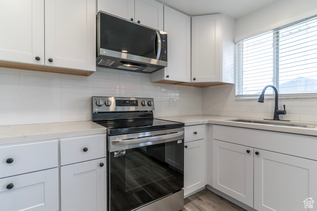 Kitchen with appliances with stainless steel finishes, a sink, tasteful backsplash, and light countertops