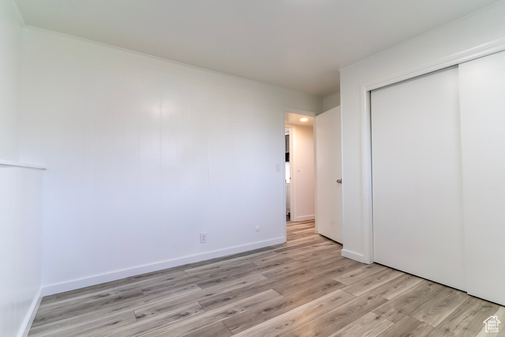 Unfurnished bedroom with light wood-type flooring, a closet, and baseboards