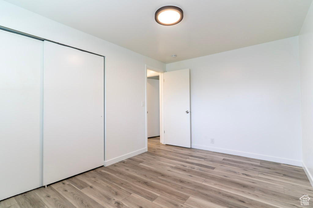 Unfurnished bedroom with light wood finished floors, baseboards, and a closet