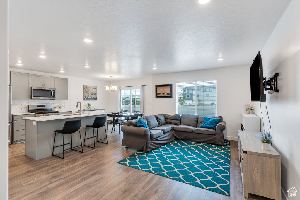 Living room with a chandelier, light wood-style floors, and recessed lighting