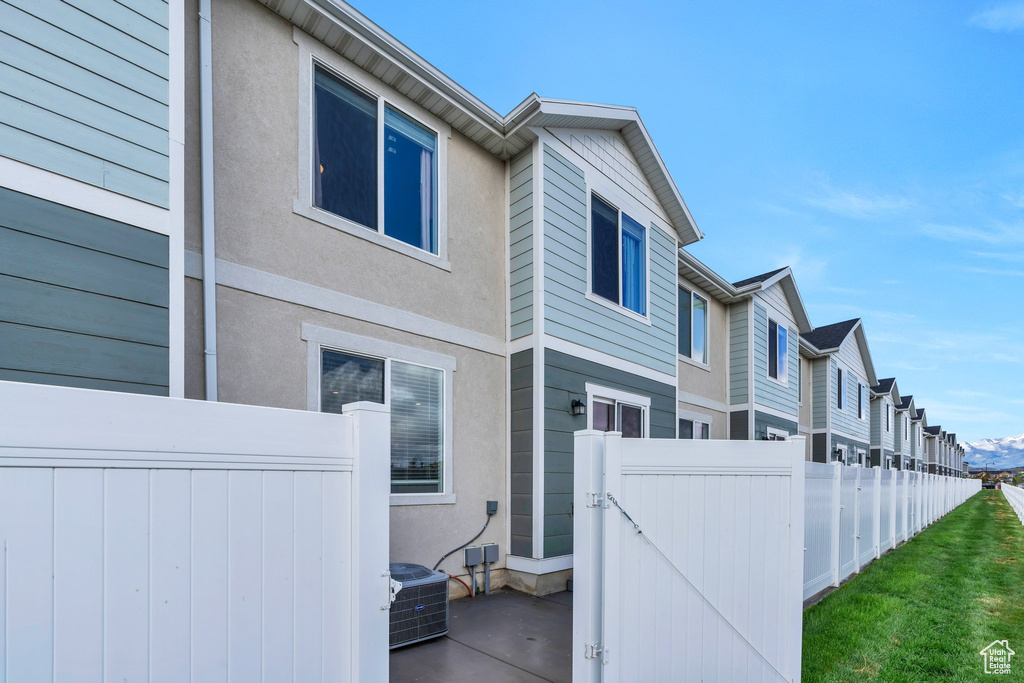 View of side of property with central air condition unit, a gate, fence, and stucco siding