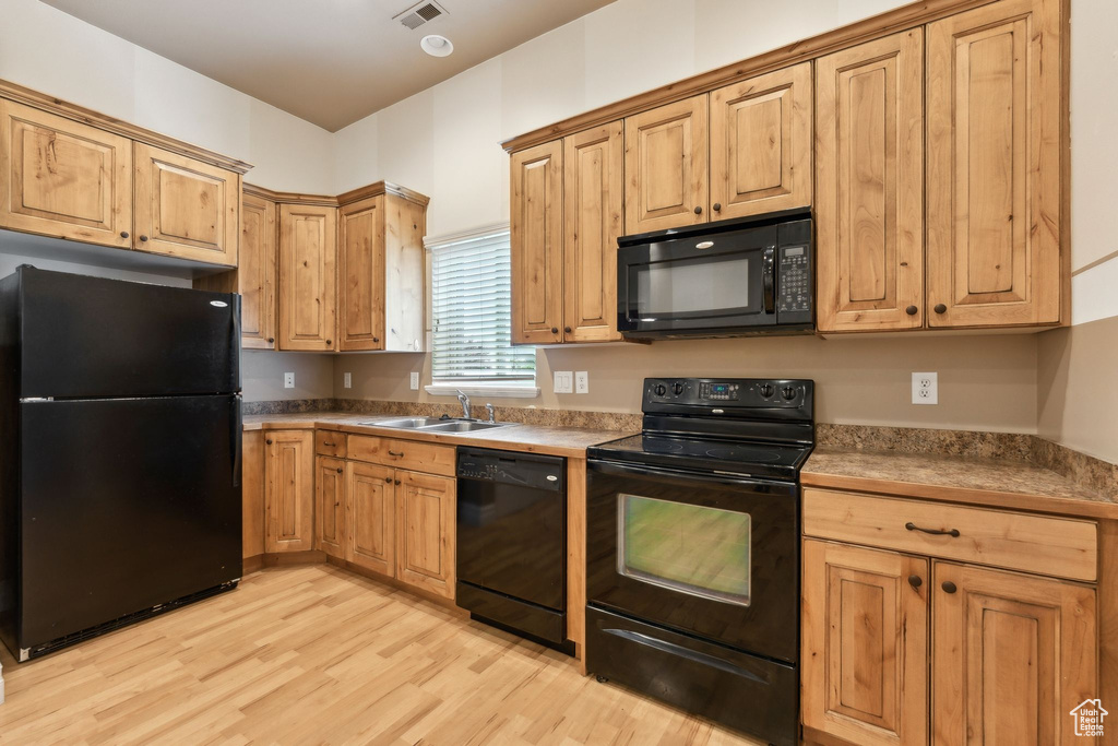 Kitchen featuring black appliances, a sink, and light wood-style flooring