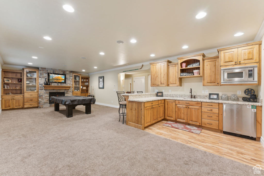 Kitchen featuring appliances with stainless steel finishes, ornamental molding, light carpet, a sink, and open shelves