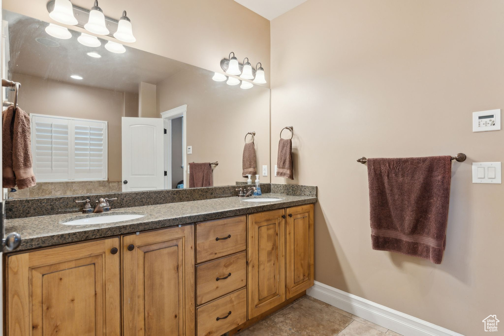 Bathroom with baseboards, double vanity, and tile patterned flooring