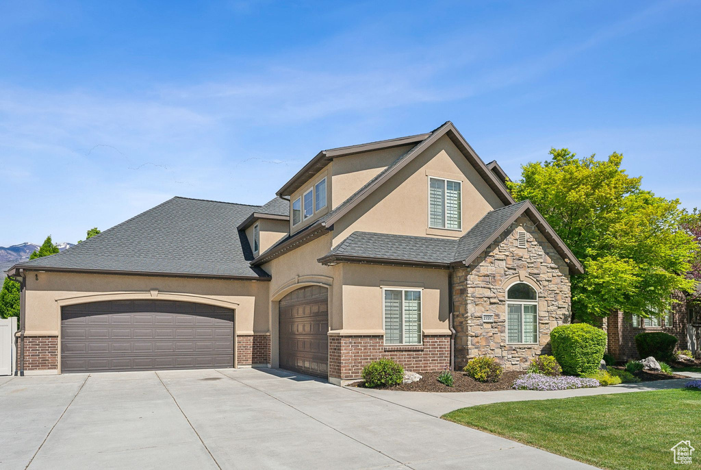 View of front of home featuring stucco siding, concrete driveway, a garage, and a front lawn