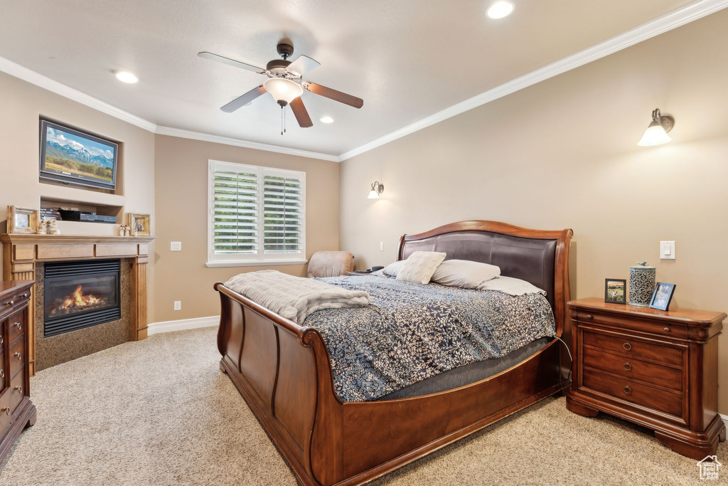 Carpeted bedroom with ornamental molding, a glass covered fireplace, baseboards, recessed lighting, and a ceiling fan