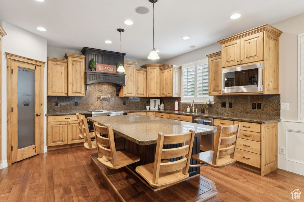 Kitchen with stainless steel microwave, light brown cabinetry, dark wood-type flooring, tasteful backsplash, and recessed lighting