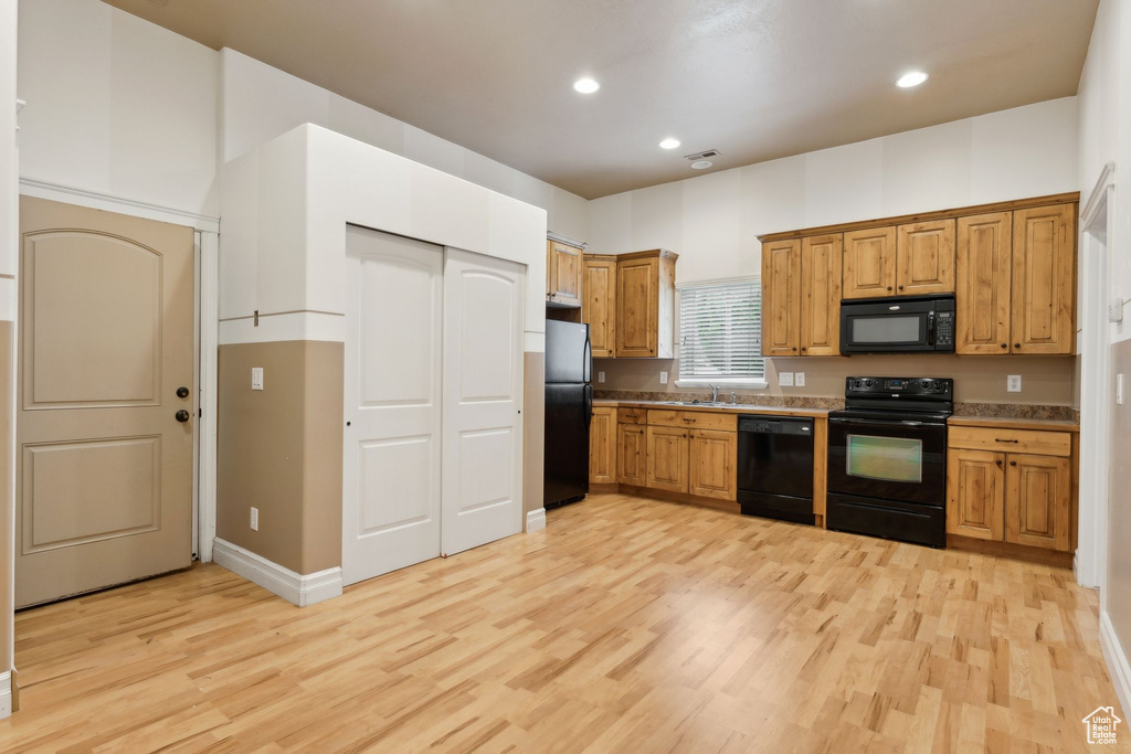 Kitchen with black appliances, light wood-style floors, a sink, recessed lighting, and brown cabinetry