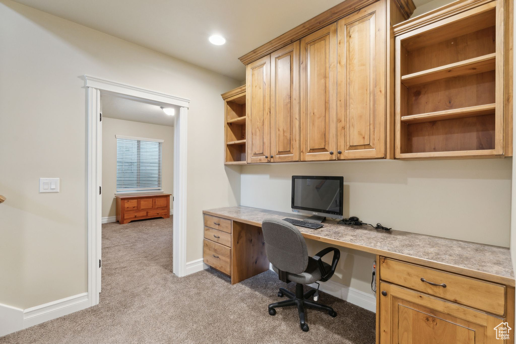 Unfurnished office with built in desk, light colored carpet, baseboards, and recessed lighting
