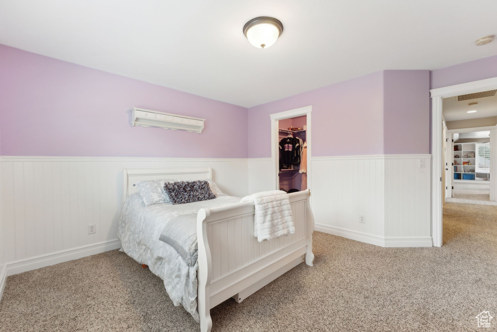 Bedroom featuring a wainscoted wall, carpet floors, a spacious closet, and a closet