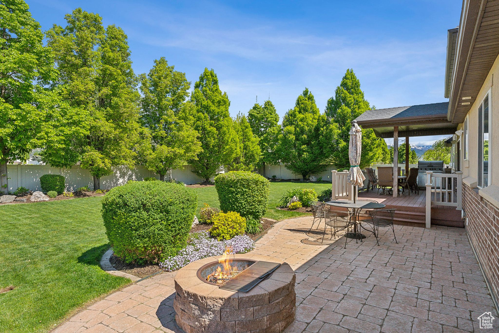 View of patio featuring an outdoor fire pit, a wooden deck, and outdoor dining space