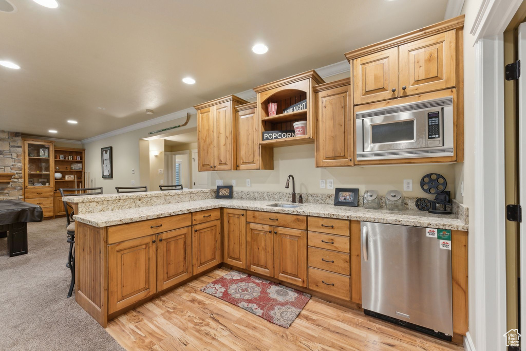 Kitchen with stainless steel microwave, fridge, a sink, a peninsula, and ornamental molding