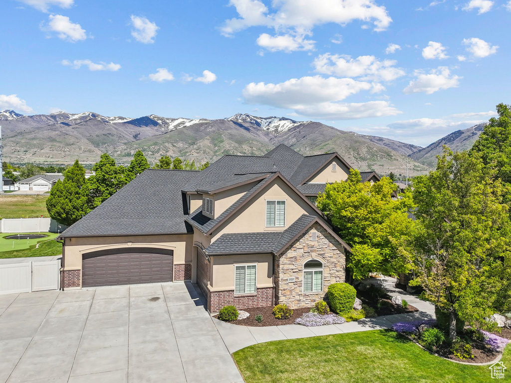 French country inspired facade with stucco siding, concrete driveway, a garage, stone siding, and a gate