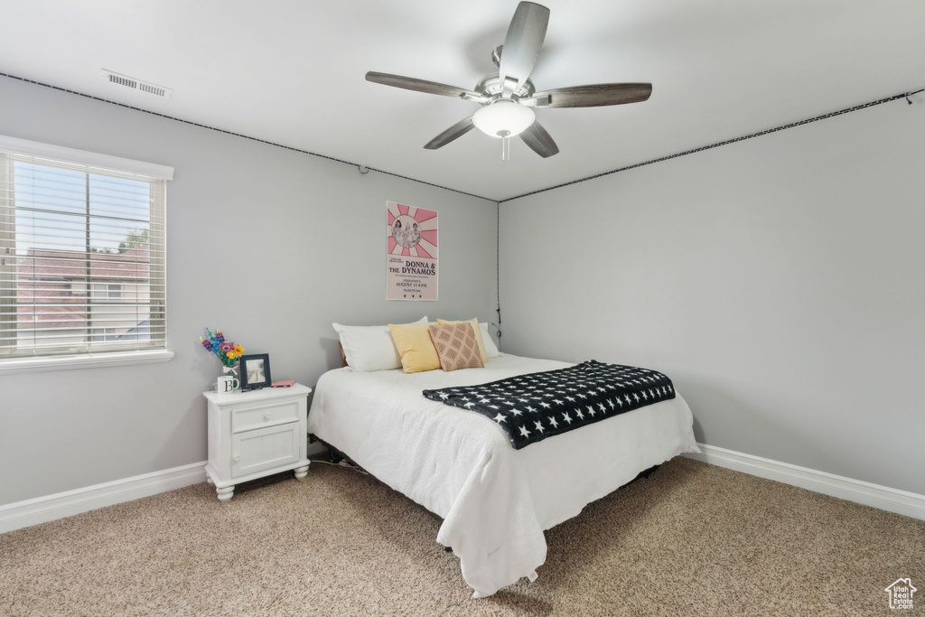 Bedroom with light colored carpet, baseboards, and a ceiling fan
