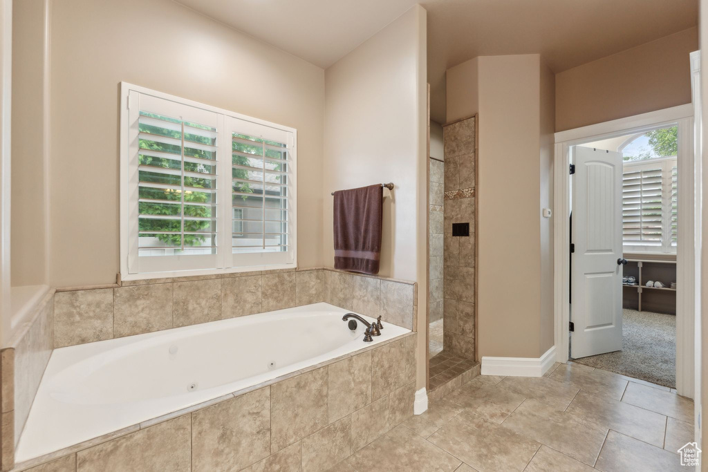 Bathroom featuring plenty of natural light, tiled shower, a tub with jets, and tile patterned flooring