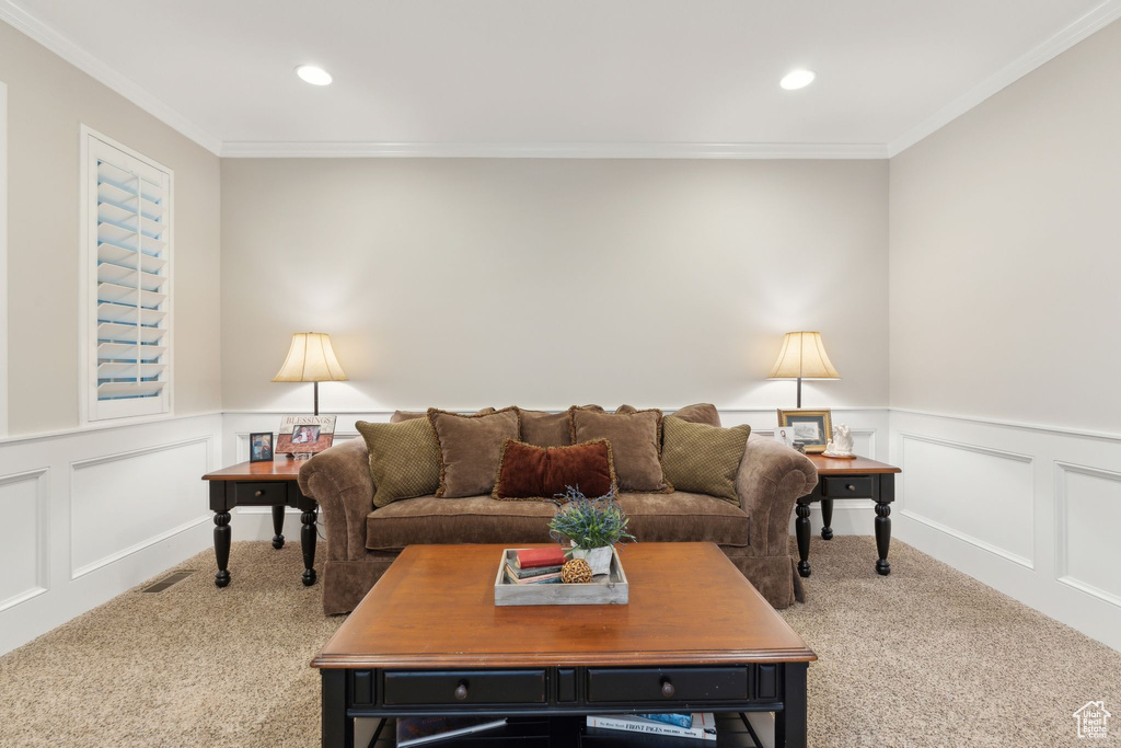 Living area featuring carpet flooring, a decorative wall, ornamental molding, and recessed lighting