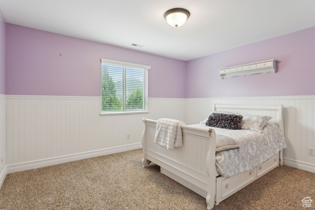 Bedroom featuring a wainscoted wall and carpet floors