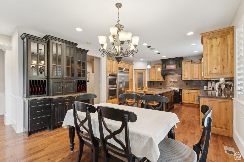 Dining room with a chandelier, wood-type flooring, and recessed lighting