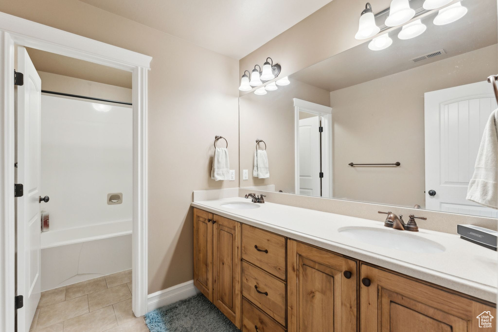 Full bath with double vanity, tile patterned floors, and tub / shower combination