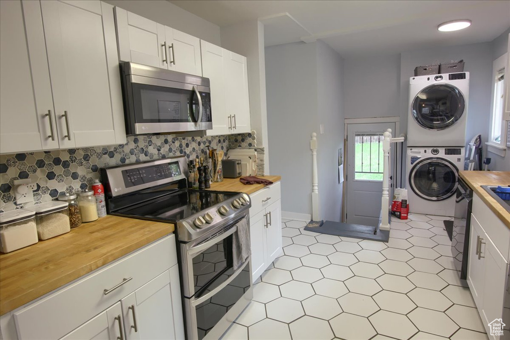 Kitchen with stainless steel appliances, stacked washing machine and dryer, butcher block counters, and plenty of natural light