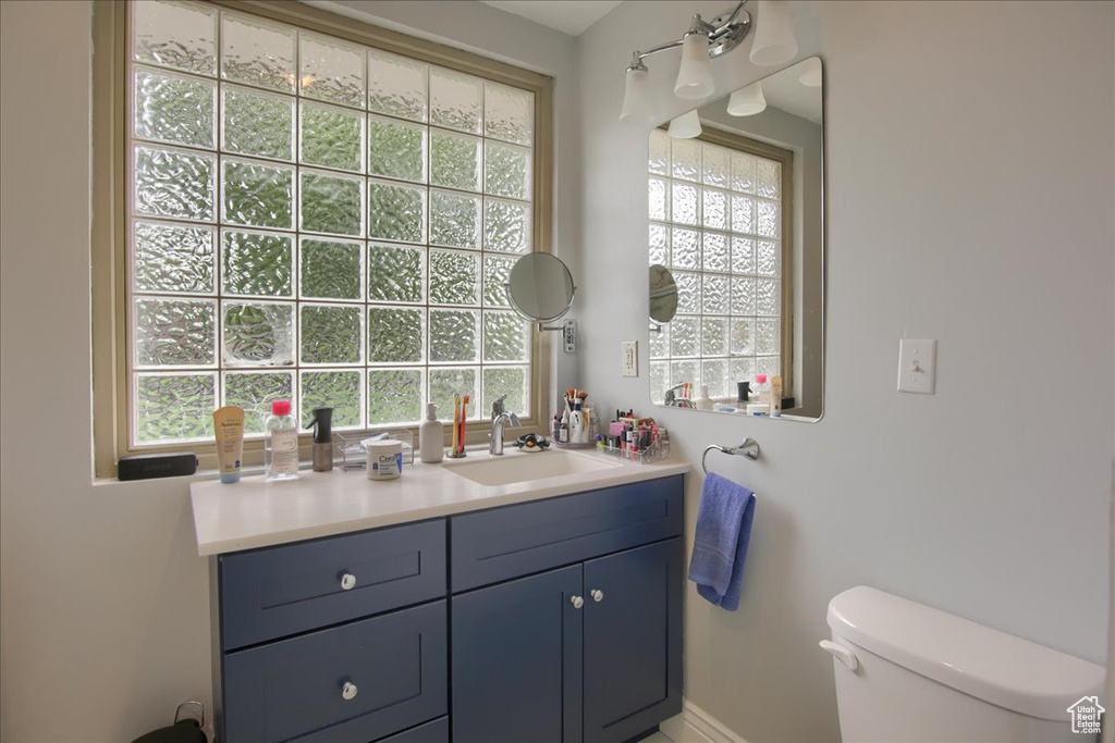 Half bath with vanity, toilet, and baseboards