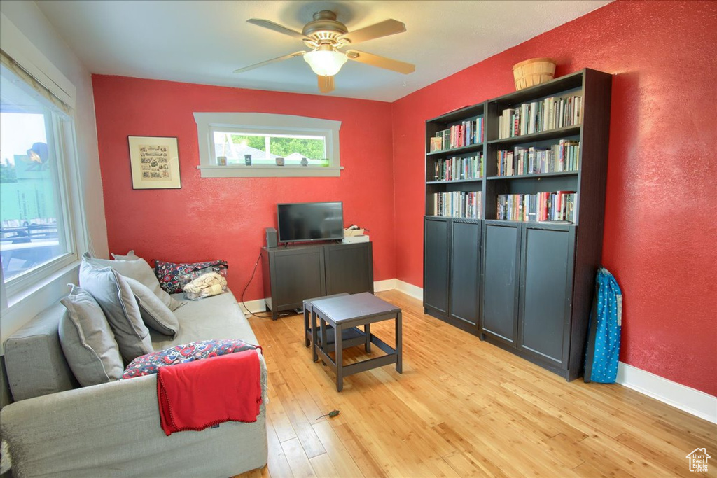 Living room with light wood-style floors, ceiling fan, healthy amount of natural light, baseboards, and a textured wall