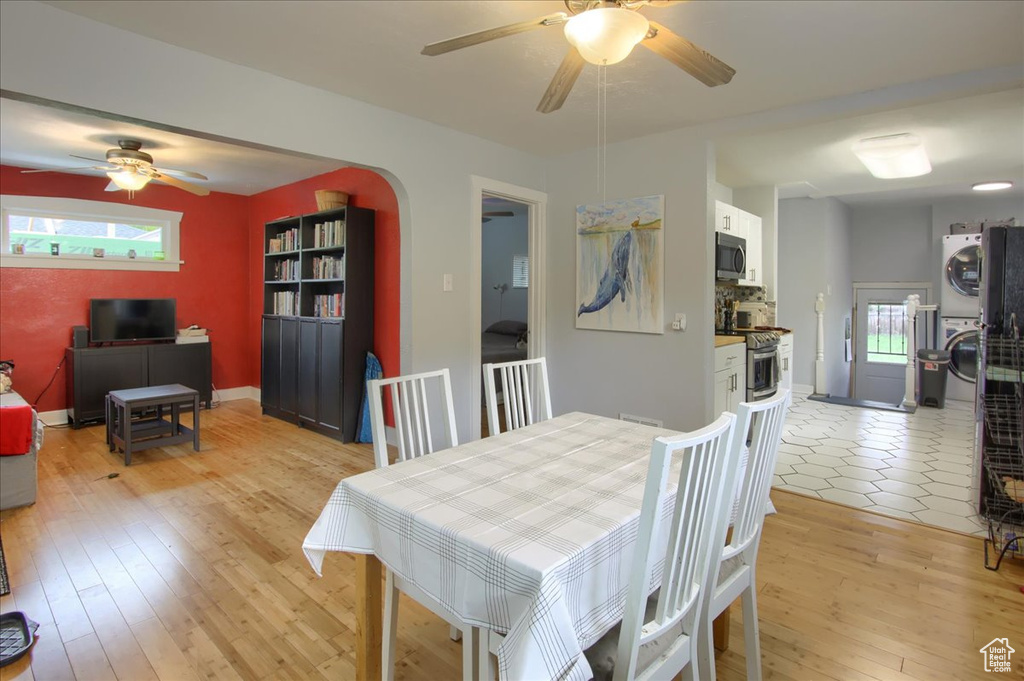 Dining room with stacked washing machine and dryer, ceiling fan, and light wood-style flooring