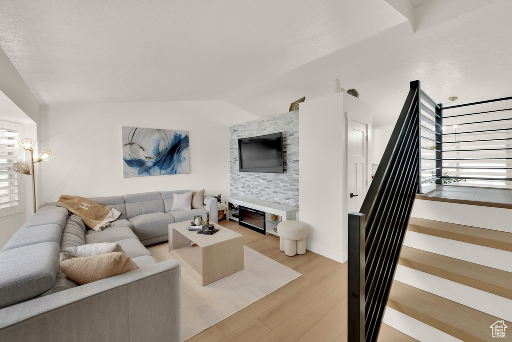 Living area with stairway, light wood finished floors, and vaulted ceiling
