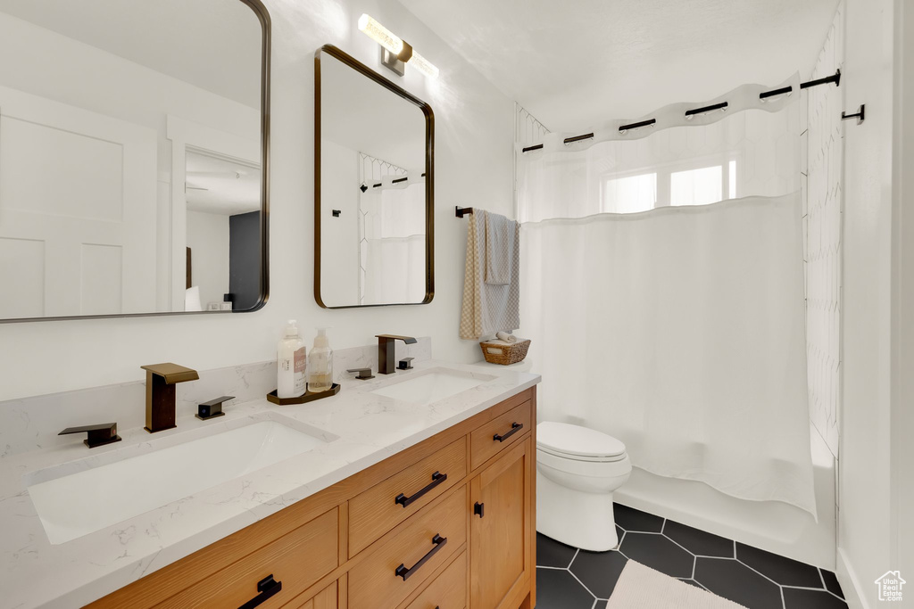 Full bathroom featuring toilet, double vanity, shower / tub combo with curtain, and tile patterned flooring