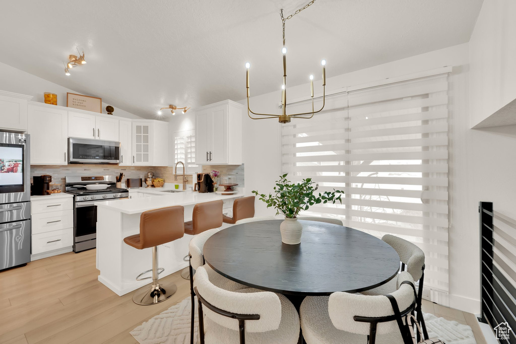 Dining room with lofted ceiling and light wood-type flooring