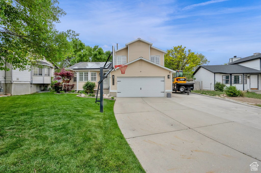 View of front of house featuring a front yard, driveway, and an attached garage
