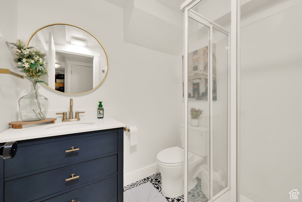 Full bathroom featuring a shower stall, vanity, toilet, baseboards, and tile patterned flooring