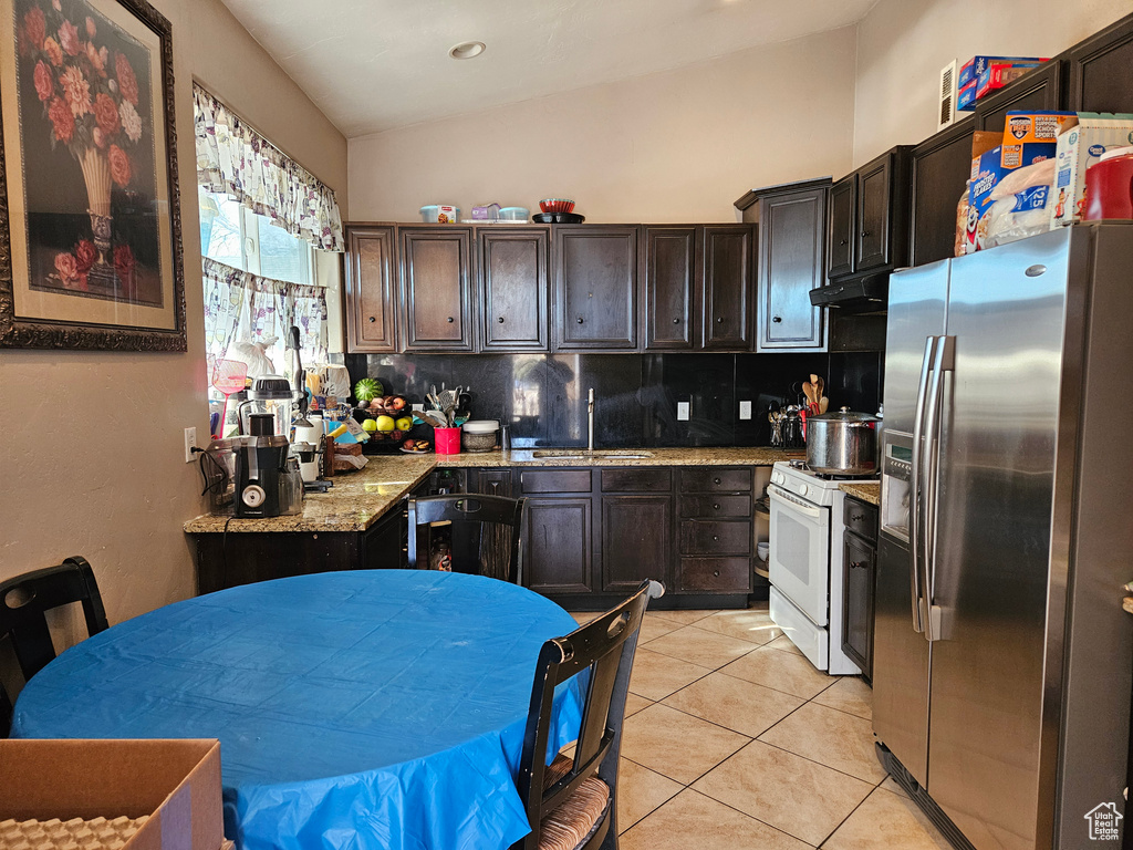 Kitchen with stainless steel fridge with ice dispenser, white range with gas stovetop, a sink, tasteful backsplash, and vaulted ceiling